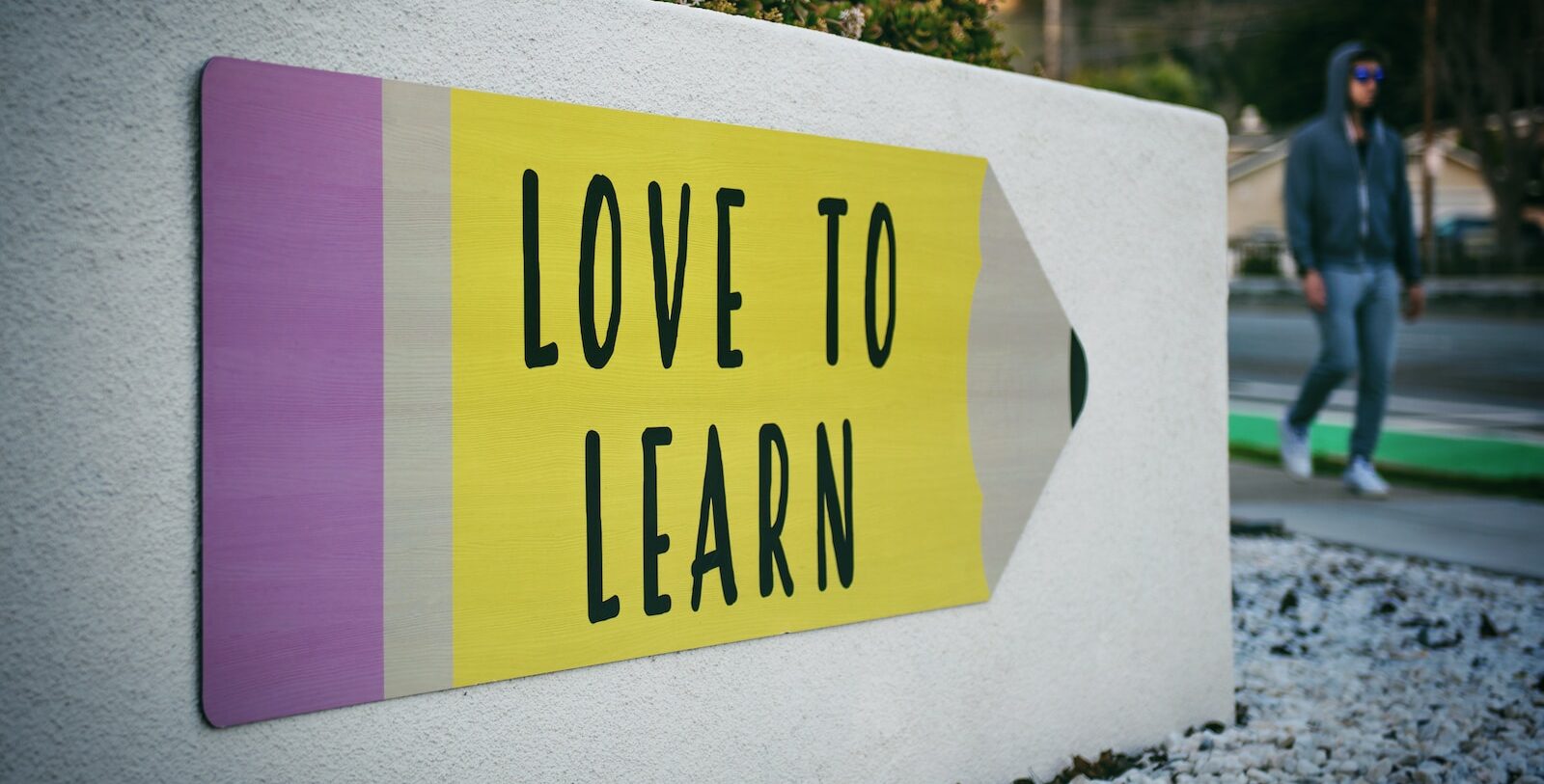 love to learn pencil signage on wall near walking man